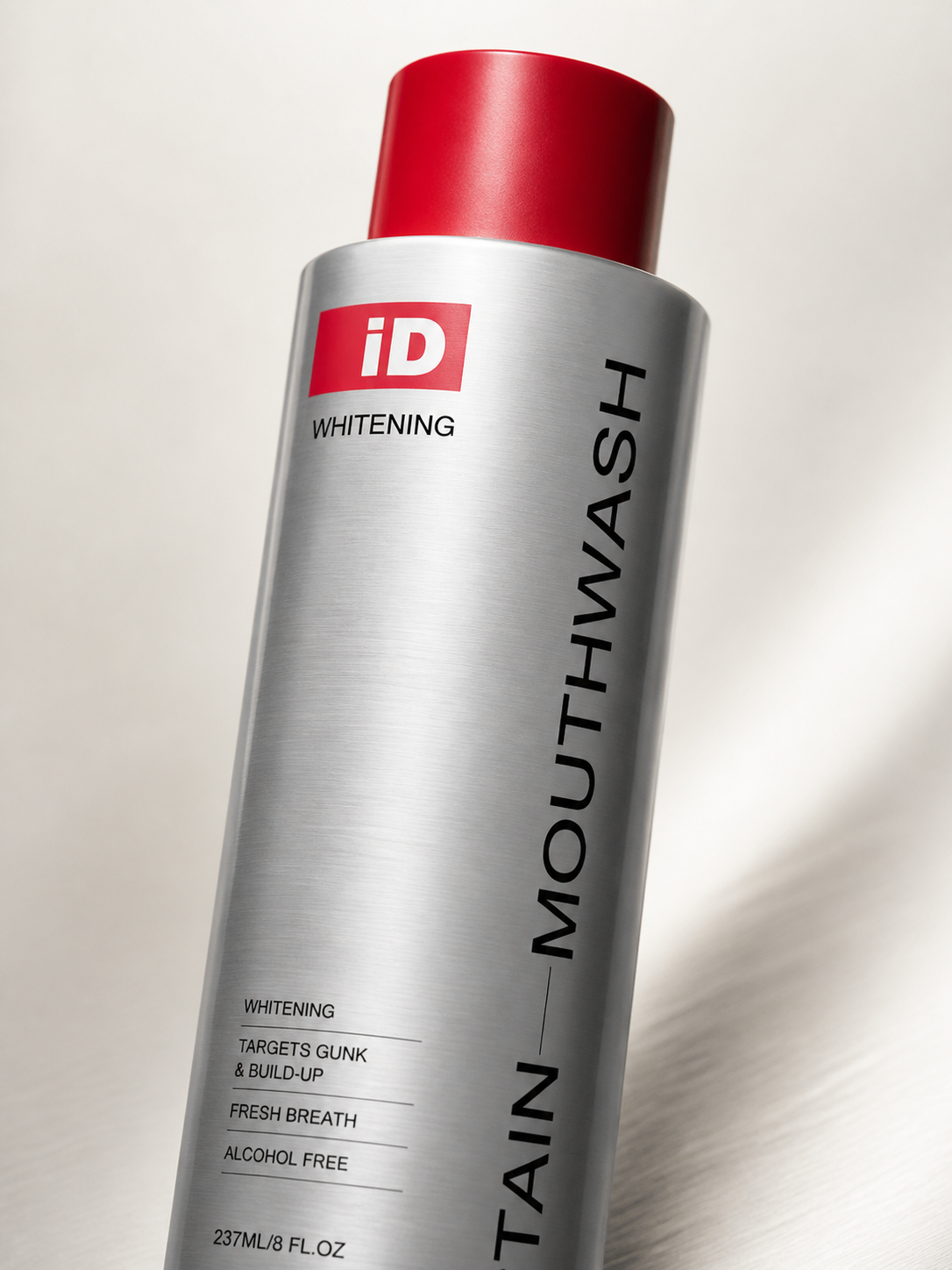 Macro detail of the original iD brushed-silver metal mouthwash bottle